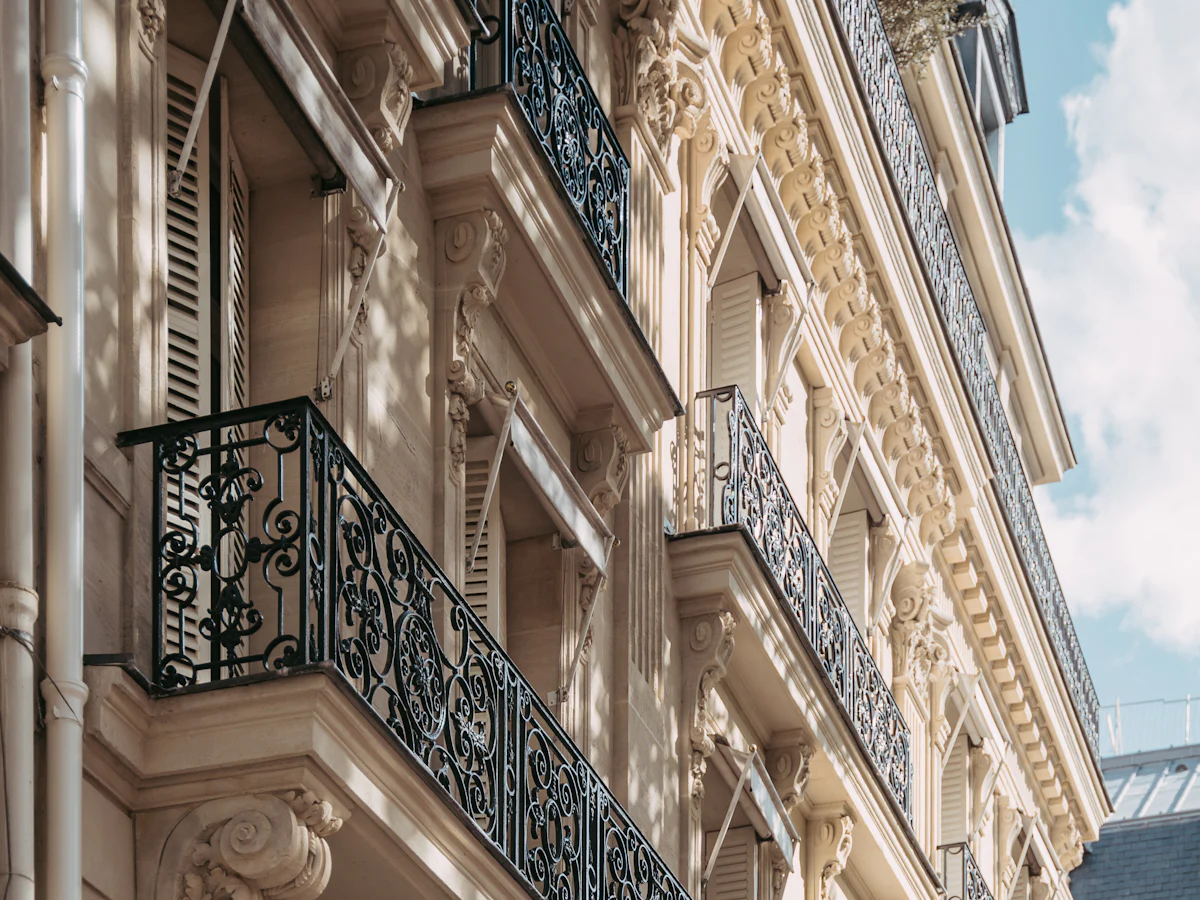 Balcons en fer forgé et modénatures sculptées d’une façade d’immeuble en pierre de taille